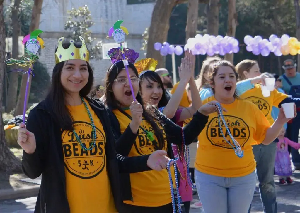 Friends in gold Dash shirts, paper crowns, and jester wands cheering along the course